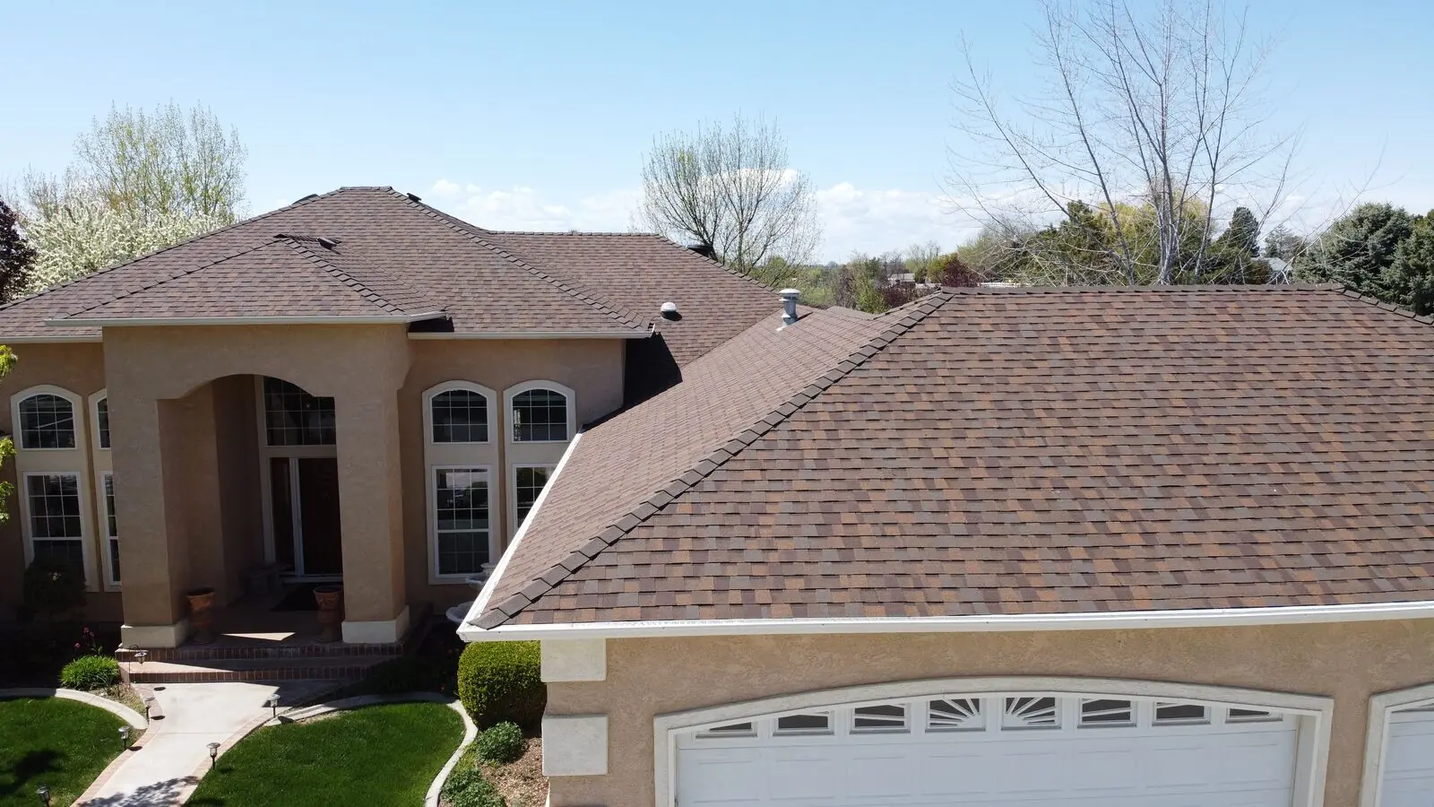 Stucco Mediterranean home with new brown shingle roof in Eagle Idaho